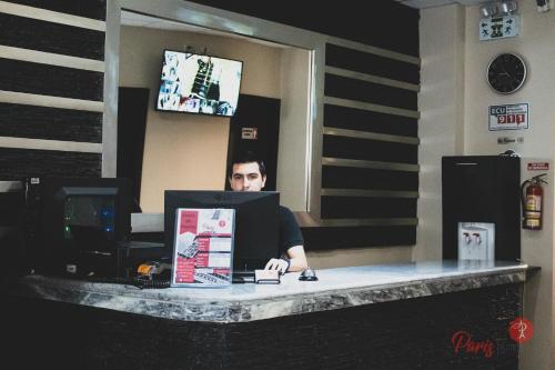 Ein Mann, der mit einem Computer am Tresen sitzt. in der Unterkunft Hotel Paris in Machala