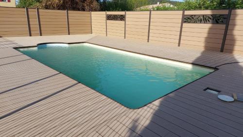 - une piscine dans un jardin avec une clôture en bois dans l'établissement Le Mas de roux Chambres d'hotes, à Bragassargues