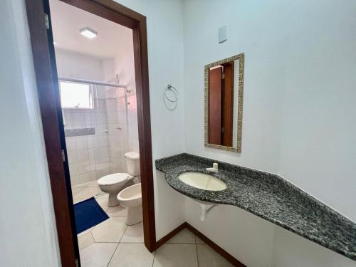 een badkamer met een wastafel, een toilet en een spiegel bij Sal De Mariscal 02 in Bombinhas