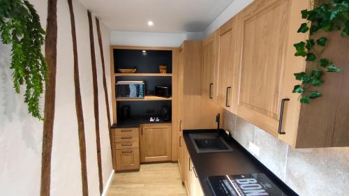 a kitchen with wooden cabinets and a sink and a microwave at Le Moulin Dort Hyper Centre Gare Disney in Meaux