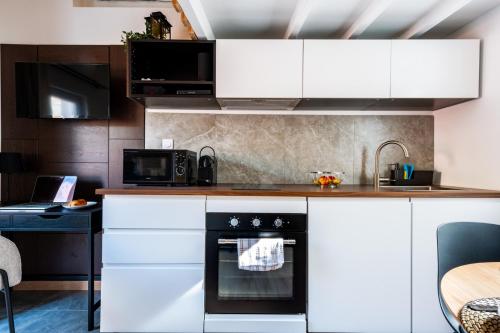 une cuisine avec des armoires blanches et un four noir dans l'établissement Hêtre tranquille - coeur de ville, à Avignon