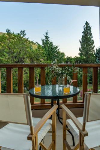 a glass table on a deck with two chairs at Platanos in Vasiliki