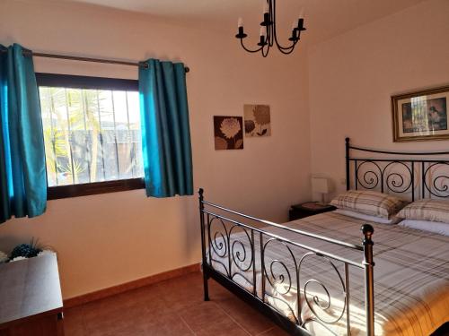 Schlafzimmer mit einem Bett mit blauen Vorhängen und einem Fenster in der Unterkunft Villa Georgiana - 4 Bed Property with private pool in Playa Blanca