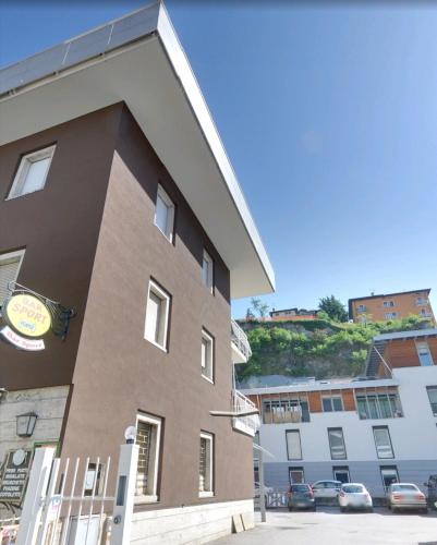 un grande edificio marrone con auto parcheggiate in un parcheggio di GREY IL NUOVO BICAMERE CON TERRAZZA E PARCHEGGIO a Trento