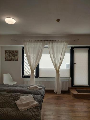 a bedroom with a bed and two windows with curtains at Студио 55 in Ruse
