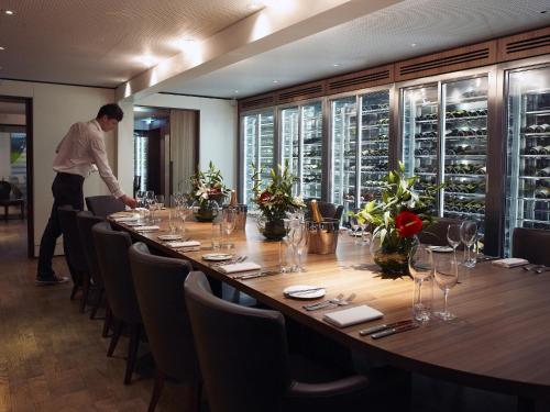 a man standing at a long table in a restaurant at Malmaison Cheltenham in Cheltenham