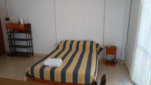 1 cama con manta a rayas en una habitación en Laprida, en Curuzú Cuatiá