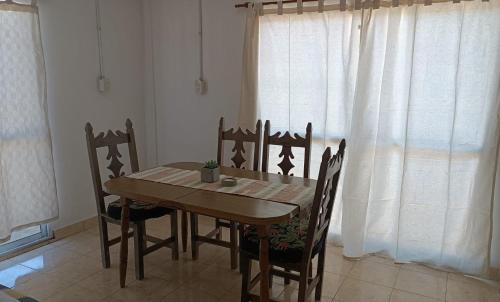 Una mesa y sillas de madera en una habitación con ventana. en Laprida, en Curuzú Cuatiá