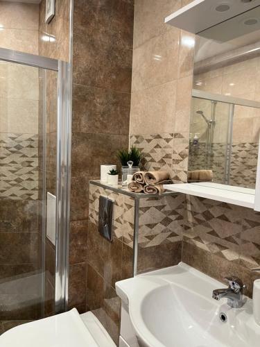 uma casa de banho com um lavatório, um chuveiro e um WC. em Azzurro Premium Apartment on Bulevard Bogoridi em Burgas