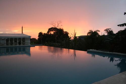 a swimming pool with a sunset in the background at Sol Pacifico Lodge in Cascajal