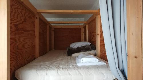 um pequeno quarto com uma cama numa casa de madeira em Sarabetsu-mura chiiki Kouryu Center - Vacation STAY 31493v em Naka-satsunai