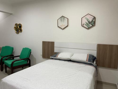 a bedroom with a bed and two green chairs at Condominio Las Palmas II VILLA FATIMA in Santa Cruz de la Sierra