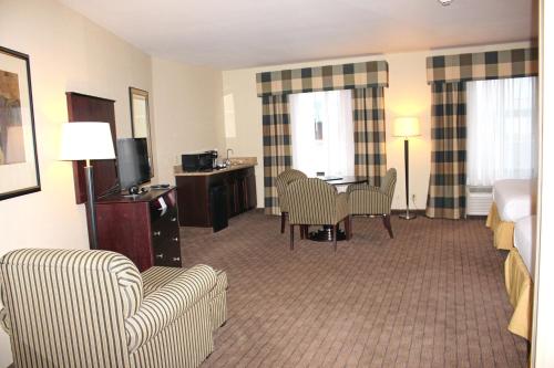 a hotel room with a bed and a table and chairs at Holiday Inn Express Hotel & Suites Syracuse North Airport Area by IHG in Cicero