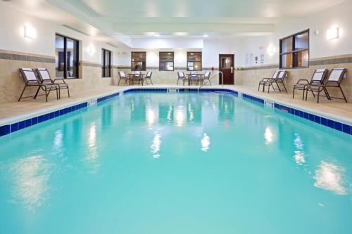 a pool in a hotel with chairs and tables at Holiday Inn Express Hotel & Suites Syracuse North Airport Area, an IHG Hotel in Cicero