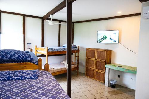 a bedroom with two bunk beds and a desk at Hotel Adventure Lodge in Jacó