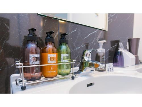 ein Waschbecken mit vier Flaschen Seife und einem Spiegel in der Unterkunft ＹＯＵ ＳＴＹＬＥ ＨＯＴＥＬ ＨＡＫＡＴＡ - Vacation STAY 16027v in Fukuoka