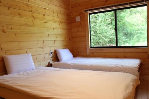 two beds in a log cabin with a window at NEXX IKI - Vacation STAY 16966v in Iki