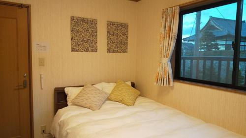 a bedroom with a bed with two pillows and a window at Guest House Nishimura - Vacation STAY 13436 in Kyoto