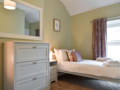 a bedroom with a bed and a dresser and a mirror at Bwthyn Talaran in Dolgellau
