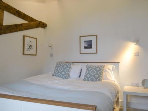 1 dormitorio con 1 cama con sábanas y almohadas blancas en Printmakers Cottage, en Bellanoch