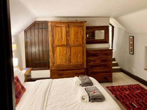 a bedroom with a bed and a wooden cabinet at Brookside Cottage in Adforton