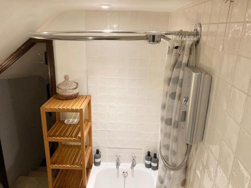 a bathroom with a tub with a shower curtain at Brookside Cottage in Adforton