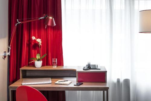- un bureau avec une lampe et un rideau rouge dans l'établissement Aparthotel Adagio Paris Bercy Village, à Paris