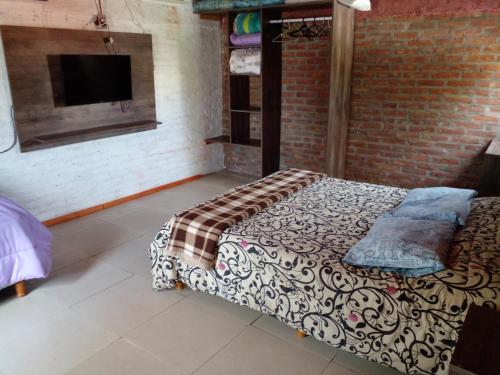 1 dormitorio con cama y pared de ladrillo en Terra II en Villa Carlos Paz