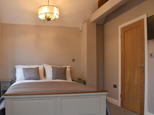 a bedroom with a white bed with a chandelier at The Cottage in Bewdley