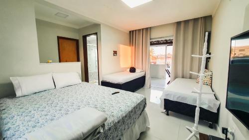 a hotel room with two beds and a window at Confortável casa em Arembepe,100 metros da Praia com Churrasqueira Piscina e Wi-fi in Arembepe