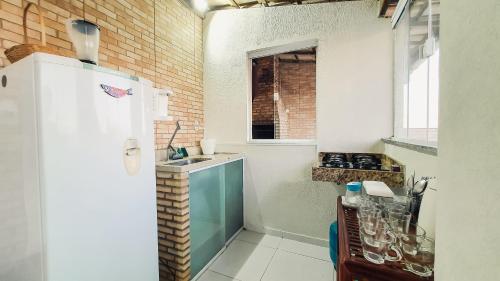 a kitchen with a white refrigerator and a sink at Confortável casa em Arembepe,100 metros da Praia com Churrasqueira Piscina e Wi-fi in Arembepe