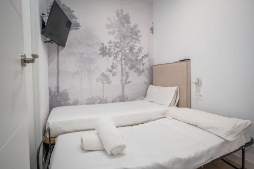 two beds in a small room with a tv at QH Avenida de la Constitución in Granada