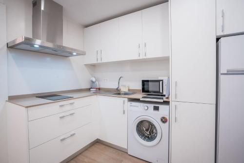 a white kitchen with a washing machine and a microwave at QH Avenida de la Constitución in Granada