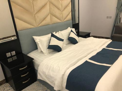 a bedroom with a large bed with white and blue pillows at قرين فيو in Abha