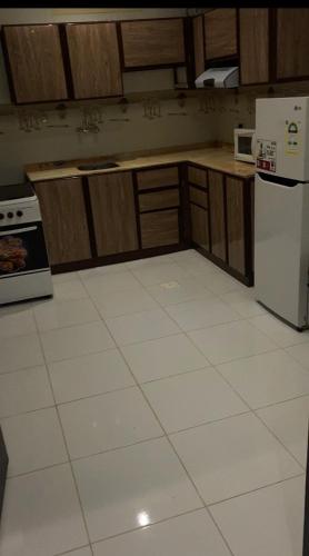 a kitchen with a white tile floor and a refrigerator at قرين فيو للشقق المخدومة in Abha