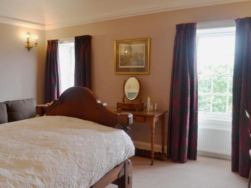 a bedroom with a bed and a mirror and windows at Culpee House in Newton Stewart