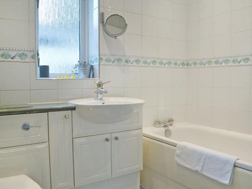 a white bathroom with a sink and a bath tub at Footdee Cottage in Aberdeen