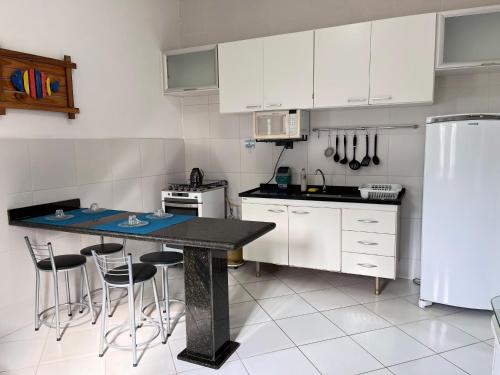 een keuken met witte kasten en een tafel met krukken bij Apartamento aconchegante com ar condicionado - Frade, Angra dos Reis in Angra dos Reis