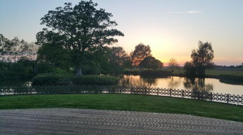 - une vue sur un lac avec un arbre et une clôture dans l'établissement Location 30 personnes, à Les Coulombray