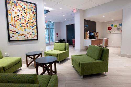 a waiting room with green chairs and a painting on the wall at Holiday Inn Express & Suites Jersey City - Holland Tunnel by IHG in Jersey City