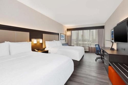 a hotel room with two beds and a flat screen tv at Holiday Inn Express & Suites Jersey City - Holland Tunnel by IHG in Jersey City