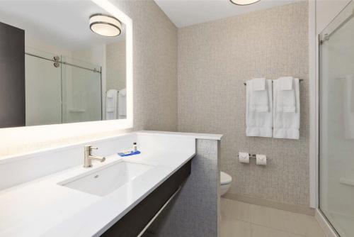 a bathroom with a sink and a toilet and a mirror at Holiday Inn Express & Suites Jersey City - Holland Tunnel by IHG in Jersey City