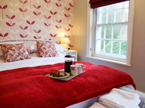 a bed with a tray of food on a red blanket at Beech Cottage in Scalby