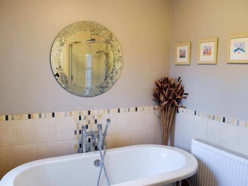 a bathroom with a tub and a mirror on the wall at Beech Cottage in Scalby