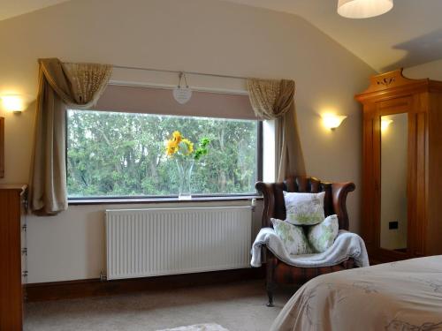 a bedroom with a window with a chair and a radiator at Carters Rest - Uk30884 in Abererch
