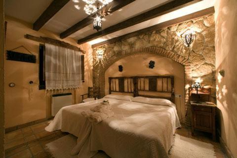 1 dormitorio con 1 cama grande en una pared de piedra en CASA RURAL MARGARITA I, en Montánchez