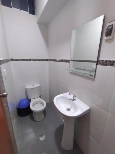 a white bathroom with a toilet and a sink at Hostal Pacífico Huánuco in Huánuco