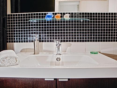 lavabo blanco en el baño con azulejos negros en Apartment Breeze en Bratislava