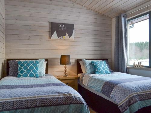 Duas camas num quarto com paredes de madeira e uma janela em Cruachan em Etteridge