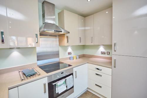 a kitchen with white cabinets and a stove top oven at Cosy,Modern and Relaxing 3 bedroom house with parking in Manchester